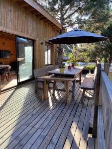 eine Holzterrasse mit Tisch und Sonnenschirm in der Unterkunft Cabaña Meliades - Bosque & Calma en Familia - Ayres Del Bosque Alojamientos in Ostende