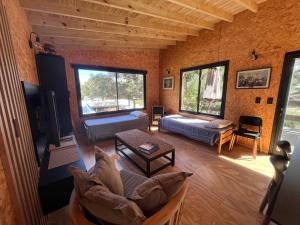 ein Wohnzimmer mit Sofa und Tisch in der Unterkunft Cabaña Meliades - Bosque & Calma en Familia - Ayres Del Bosque Alojamientos in Ostende