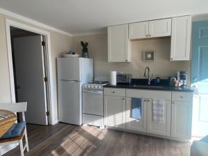 Una cocina con gabinetes blancos y un refrigerador blanco. en Shoreline Suite, en Old Orchard Beach