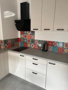 a kitchen with white cabinets and tiles on the wall at Ruczaj Cozy Room in Krakow