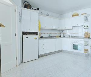 a kitchen with white cabinets and a white refrigerator at Luxor in Los Cristianos