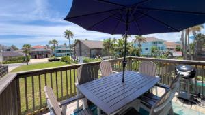 une table avec un parasol sur un balcon dans l'établissement Modern Beach Home with Pool Steps Away, à South Padre Island