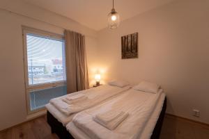 a bedroom with a bed with white sheets and a window at Snowflake XII Family rooms in Rovaniemi