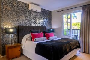 a bedroom with a bed with red pillows and a window at Baruch Guesthouse on Lovell in Stellenbosch