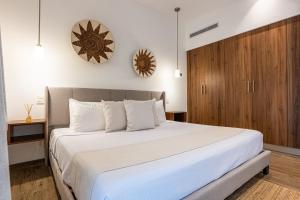 Schlafzimmer mit einem weißen Bett und einem Holzschrank in der Unterkunft The Leaf C108 in Playa del Carmen + 40 Fotos
