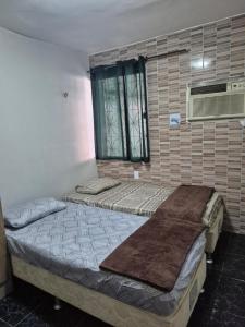 deux lits dans une chambre avec une fenêtre dans l'établissement Casa Dormitório na Cidade Nova 8 próxima da Vila cop 30, à Ananindeua