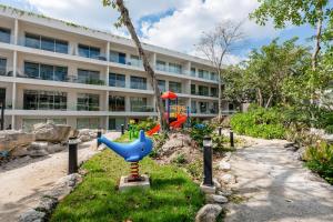ein Gebäude mit einem Spielplatz vor einem Gebäude in der Unterkunft The Leaf C108 in Playa del Carmen
