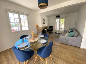 a living room with a glass table and blue chairs at TY AR POKOU Carantec in Carantec