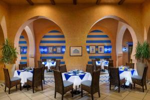un restaurant avec des tables et des chaises blanches et des murs bleus dans l'établissement JAZ Belvedere, à Charm el-Cheikh 43 autres photos