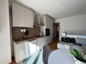 a kitchen and living room with white cabinets and a couch at Siera View Apartment - Comfort e Relax a Sappada in Ecche