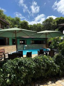 a patio with tables and umbrellas and a pool at Pousada Morada da Praia - Ubatuba -Praia Grande in Ubatuba