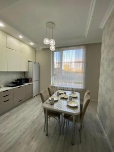 eine Küche und ein Esszimmer mit Tisch und Stühlen in der Unterkunft Уютная квартира на центре города, возле EXPO in Astana