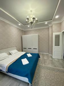 ein Schlafzimmer mit einem blauen Bett und einem Kronleuchter in der Unterkunft Уютная квартира на центре города, возле EXPO in Astana + 6 Fotos
