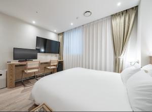 Un dormitorio con una cama y un escritorio con televisión. en 호텔 레이블 안산, en Chungang-yŏk