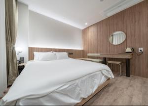 Un dormitorio con una gran cama blanca y un escritorio. en 호텔 레이블 안산, en Chungang-yŏk