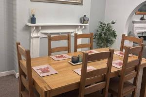 a wooden dining room table with four chairs at 3 Bed House-Sleeps 5-Free Parking & Wi-Fi in Sketty