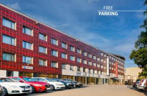 a red building with cars parked in a parking lot at Iris Hotel Eden - Czech Leading Hotels in Prague