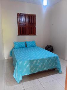 a bedroom with a bed with blue sheets and a window at Casa c wifi, 2 Qts, 3 camas, ganchos p redes e estacionamento in Santarém