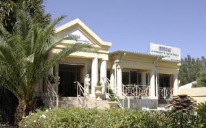 ein weißes Haus mit einer Palme davor in der Unterkunft Lajava Guest Lodge in Krugersdorp