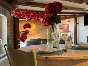 a table with a vase of red flowers on it at Siesta by Rentoom in Toruń