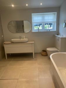 a bathroom with a sink and a tub and a mirror at Summerhouse Denmark in Tisvildeleje 700 m walk from beach in Tisvilde +14 photos