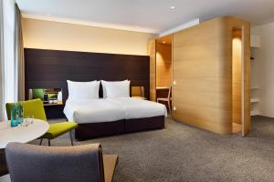 a hotel room with a bed and a table and chairs at Dorint Parkhotel Jordanbad in Biberach an der Riß