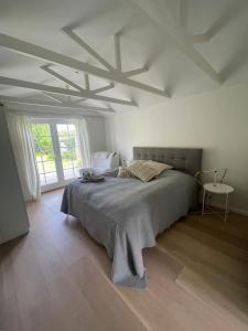 a white bedroom with a large bed and a window at Summerhouse Denmark in Tisvildeleje 700 m walk from beach in Tisvilde