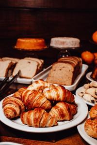 a table topped with plates of croissants and bread at Pousada Charm Canela in Canela