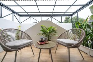 two chairs and a table on a balcony with plants at VivaDeva , Pool Villa In Nimman 4BR Near MAYA MALL in Chiang Mai