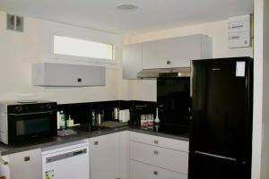 a kitchen with white cabinets and a black refrigerator at Issam in Lyon +29 photos