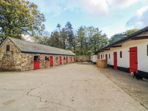 a group of barns with red doors and a driveway at Robins Rest at The Lodge in McGrathʼs Cross Roads