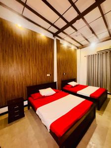 Un dormitorio con dos camas con sábanas rojas y blancas. en Shehan Villa, en Beruwala