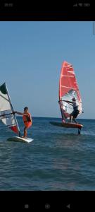 two people are windsurfing in the ocean on the water at Casa Marirò in Marina di Ragusa