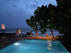 ヒッカドゥワにあるAt Ease Beach Hotelの夜間のビーチ横のスイミングプール