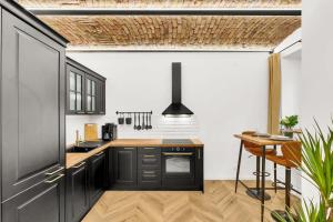 a kitchen with black cabinets and a wooden table at The Magnificent Urban Hideaway in Bratislava