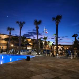 a building with palm trees and a swimming pool at night at Island House BeachFront Condo Hotel in Corpus Christi