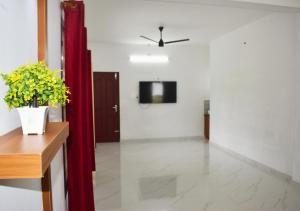 a living room with a television and a red curtain at MeadowView Cottage Marari in Mararikulam