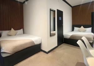 - 2 lits dans une chambre avec des chaises et un miroir dans l'établissement Amsterdam Hotel, à Londres