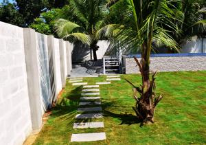 un jardin avec un palmier et un chemin en pierre dans l'établissement MeadowView Cottage Marari, à Mararikulam