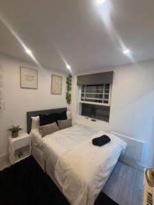 a bedroom with a large white bed with a window at Beautiful new build studio in London in Sutton