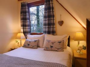 ein Schlafzimmer mit einem Bett mit Kissen und einem Fenster in der Unterkunft Ericht Holiday Lodges in Blairgowrie