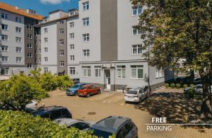 プラハにあるCOLORFACTORY SPA Hotel - Czech Leading Hotelsの建物の前に車が駐車されている駐車場