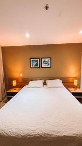 a bedroom with a large white bed with two lamps at Apartamento em Duque de Caxias in Duque de Caxias