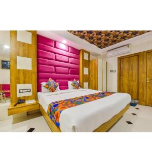 ein Schlafzimmer mit einem großen Bett mit einer rosa Wand in der Unterkunft HoTEL SIGNOR AIRPORT INDORE in Indore + 16 Fotos