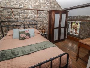 a bedroom with a bed and a stone wall at Arian in Aber-nant
