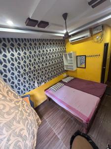 a small room with a bed and a yellow wall at Jsn Palace in Chennai +9 photos