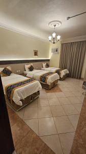 a hotel room with three beds and a chandelier at Lamar 1 furnished Aparthotel in Riyadh