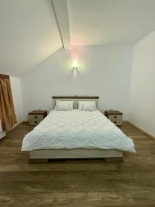 Un dormitorio con una cama blanca con dos mesitas de noche. en Imperial, en Moisei