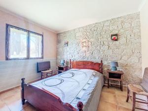 ein Schlafzimmer mit einem Bett und einer Steinwand in der Unterkunft Holiday Home La Grange Jacques by Interhome in Dondas