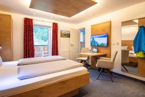 a bedroom with a bed and a desk and a table at Das Kleemanns in Mittelberg